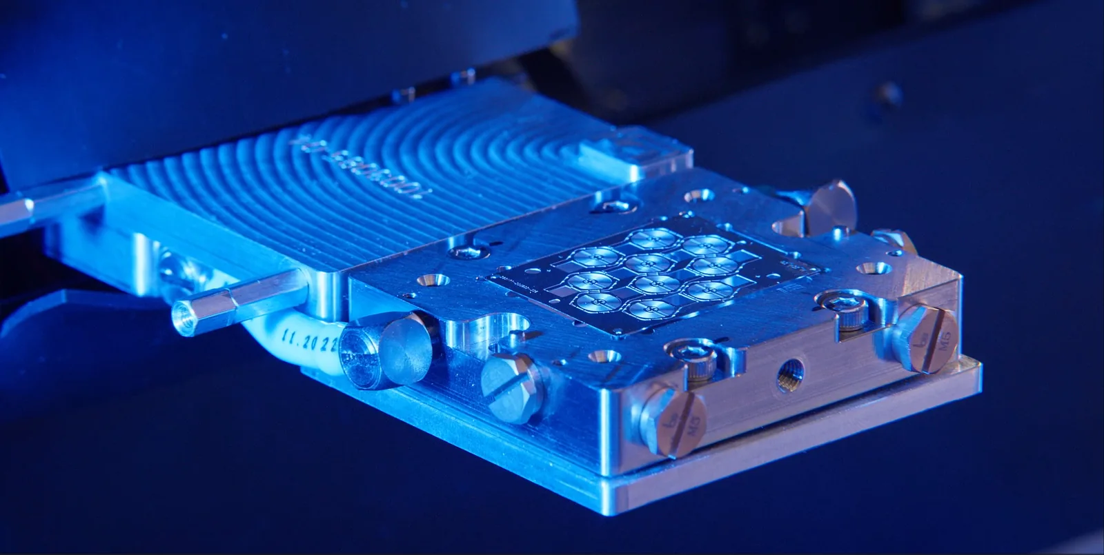 A machine head lowered over a gridded metal block